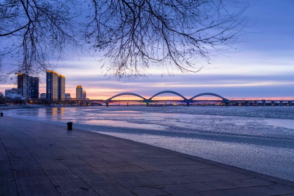 Pont ferroviaire 松花江铁路大桥 au coucher de soleil – Vue sur la rivière Songhua gelée