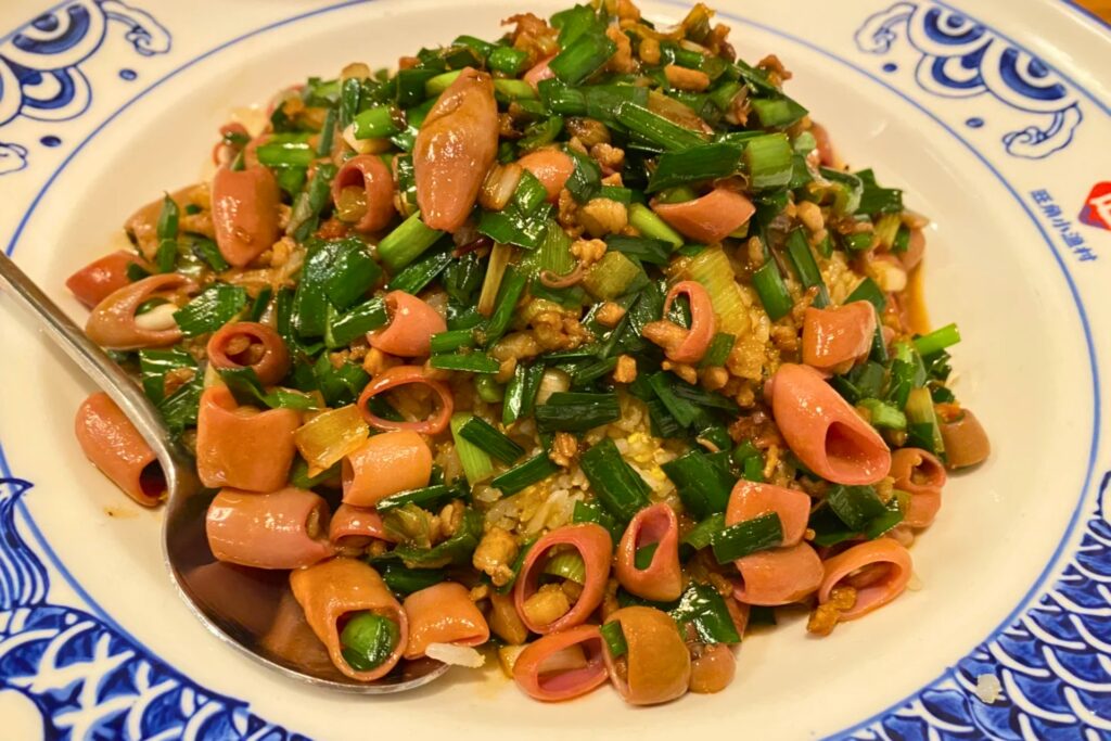 Assiette de riz sauté au ver de mer de Qingdao, garnie d’échalotes et de légumes, servie dans un plat en porcelaine