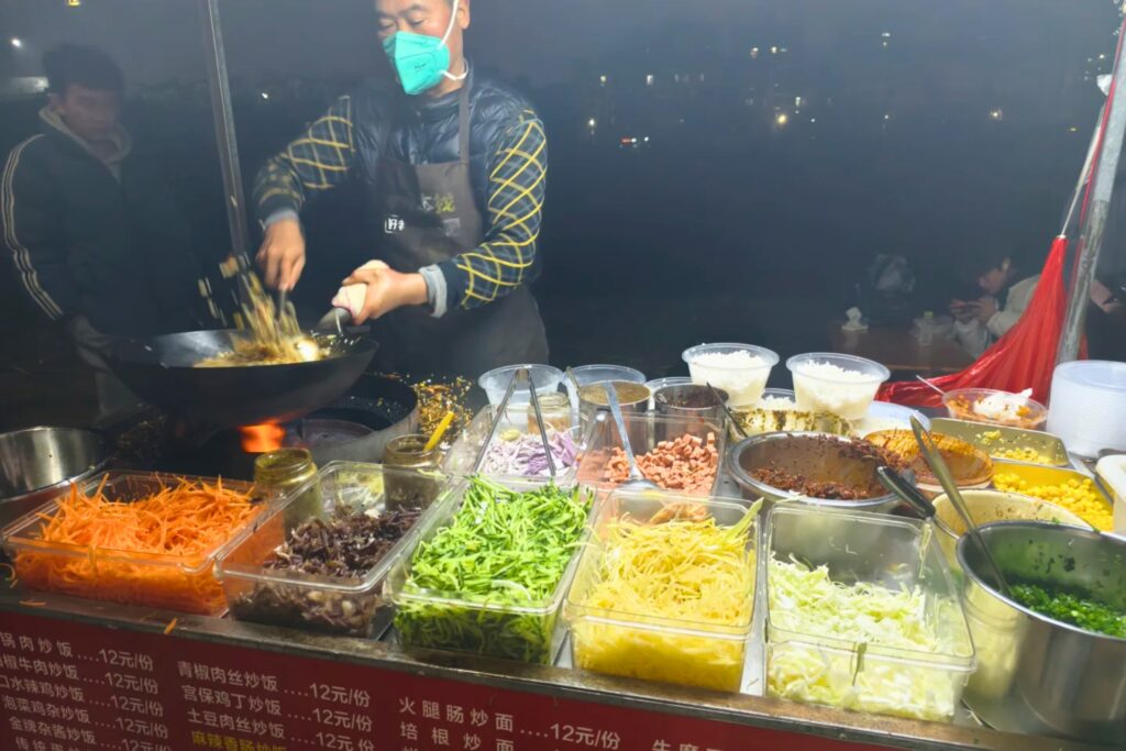 Cuisson à très haute température au wok dans un stand de street food en Chine, garantissant l'élimination des bactéries. 3. Photo _Le Piège à éviter_ (Fruits)