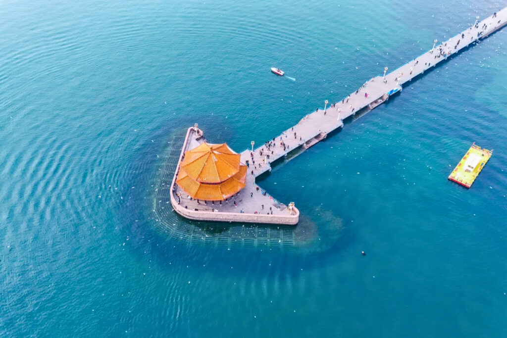 Jetée 栈桥 Zhànqiáo de Qingdao avec le pavillon 回澜阁 Huílángé et les vagues sous un ciel bleu
