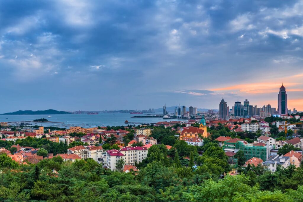 Panorama de Qingdao depuis Signal Hill, montrant les toits rouges de la vieille ville, la mer et la skyline moderne au coucher du soleil