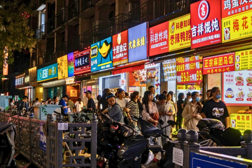 Scène de rue à Shenzhen le soir, petites échoppes locales entre vapeur, wok et néons