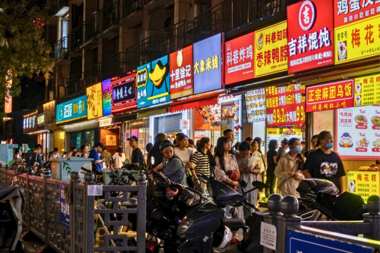 Scène de rue à Shenzhen le soir, petites échoppes locales entre vapeur, wok et néons