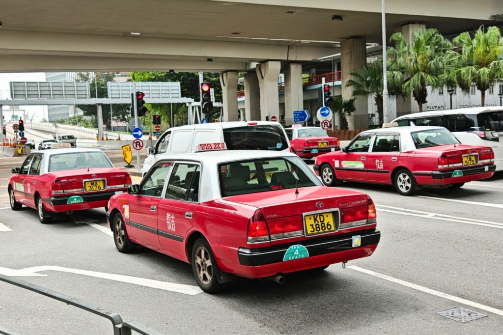 Taxi rouge dans les rues de Hong Kong, symbole du rythme urbain rapide et dense de la ville.